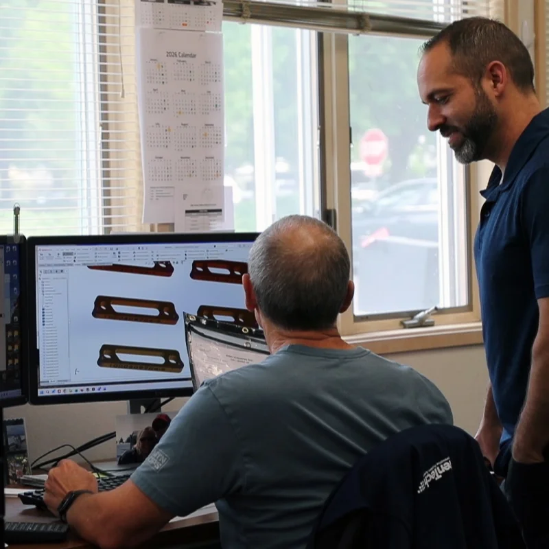 Two engineers discussing PCB CAD layout on workstation monitor